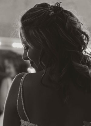 Black and white silhouette portrait of a bride with curled hair and a strapped dress in soft lighting.
