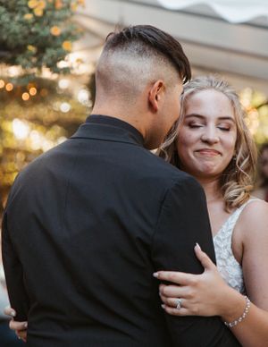 A couple shares an intimate moment during their wedding photoshoot with warm sunset lighting in the background.