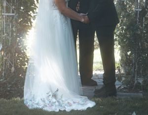 A close-up view of a wedding dress train with delicate lace details in an outdoor garden setting.