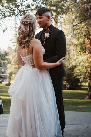 A romantic outdoor wedding moment captured between a couple in formal attire during golden hour.