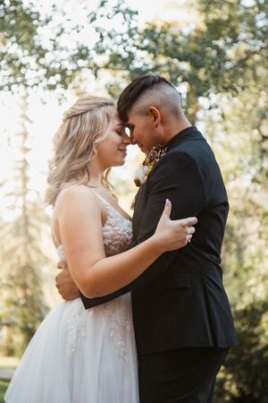 A romantic moment between newlyweds in formal attire outdoors.