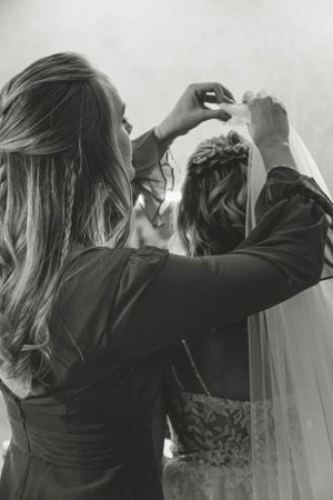 A close-up shot of someone adjusting a bridal veil in black and white.