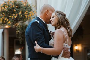 A tender embrace between newlyweds during their first dance at an evening wedding reception.