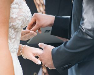 Close-up of hands exchanging wedding rings during a marriage ceremony.