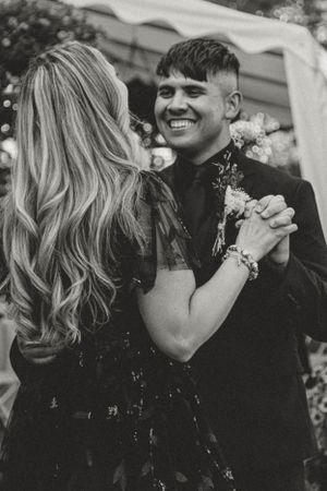 A black and white photo of a couple dancing together at an outdoor celebration with joyful expressions.
