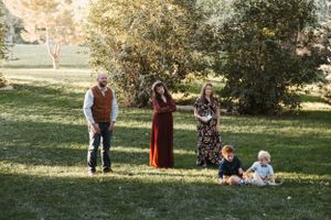 A group gathers in a sunlit park on an autumn afternoon with trees and grass in the background.