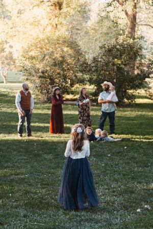 A group gathers on a grassy lawn at sunset with trees in the background.
