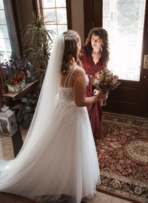 A wedding dress fitting moment in an elegant room with ornate decor and natural lighting.