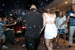 People dancing and celebrating at a party with confetti falling in the air during a nighttime celebration.