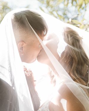 A romantic wedding moment captured under a delicate veil with soft sunlight streaming through.