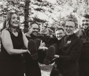 A group of people share a candid laughing moment together outdoors in black and white photography.