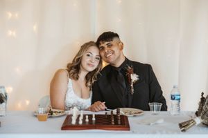 A couple playing chess at their wedding reception with twinkle lights in the background.