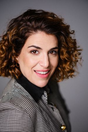 Expressive portrait with natural curls wearing black and white houndstooth jacket.
