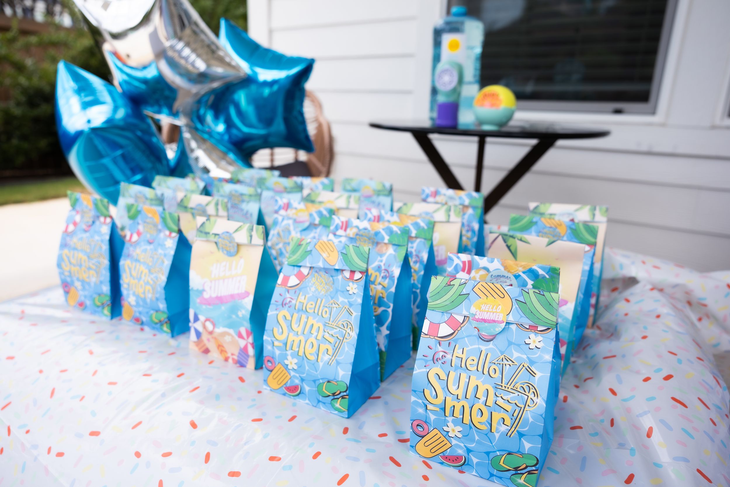 Colorful party favor bags and blue balloons arranged on a decorated table for a special event.