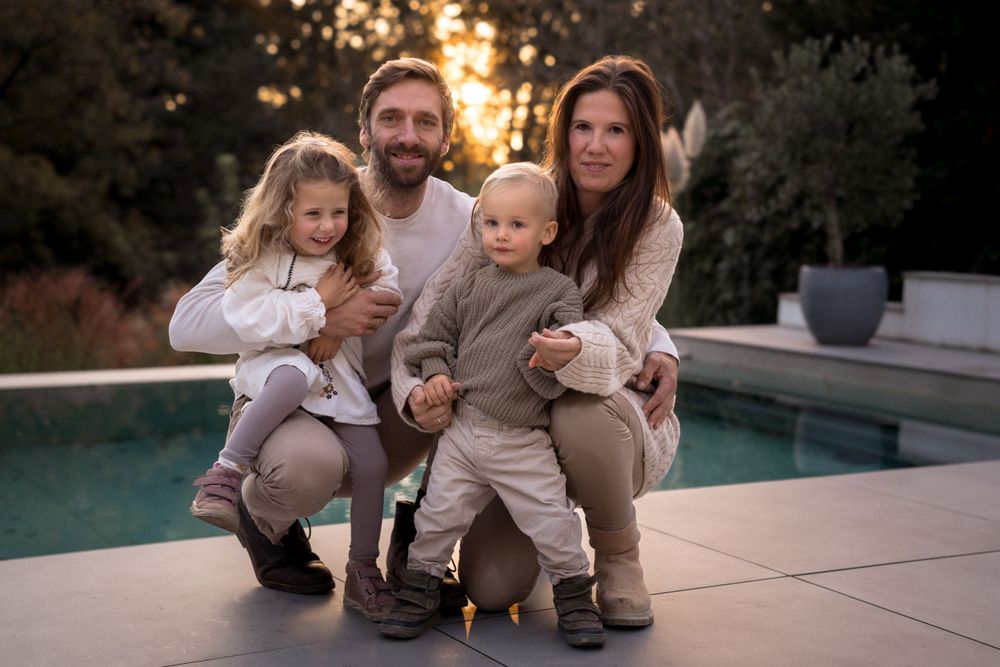 Familienporträtsitzung mit warmem Sonnenuntergangslicht an einem modernen Pooldeck.