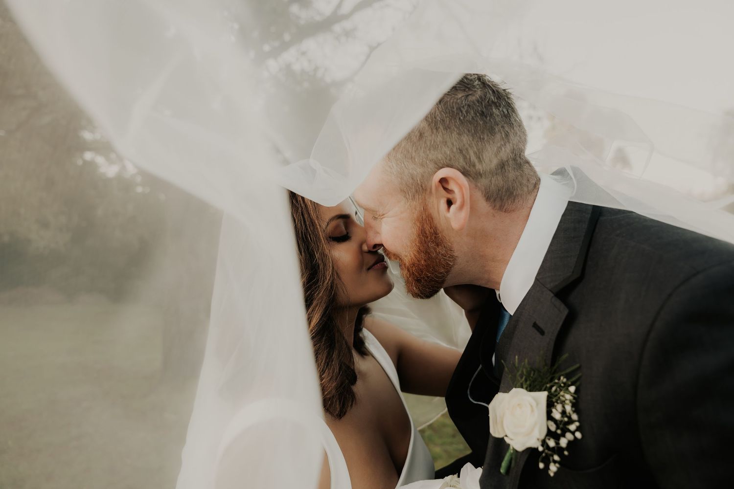 Intimate wedding moment captured with couple's veil flowing in the wind.