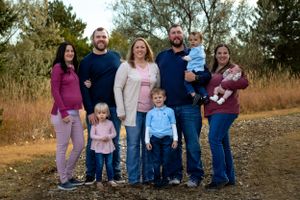 Extended family group poses together on a dirt path surrounded by autumn foliage.