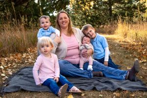 Family group sits together on blanket outdoors during autumn photoshoot.