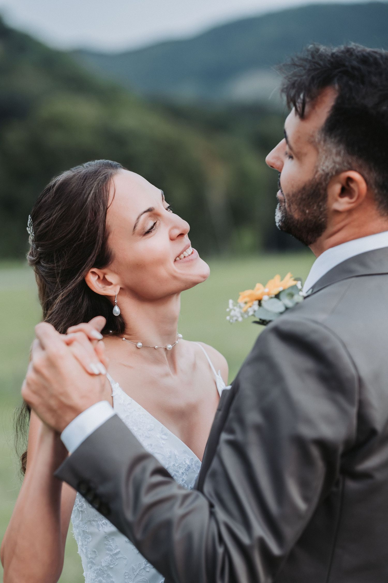 Happy newlyweds pose together, bride holding eucalyptus bouquet with groom in checkered suit.