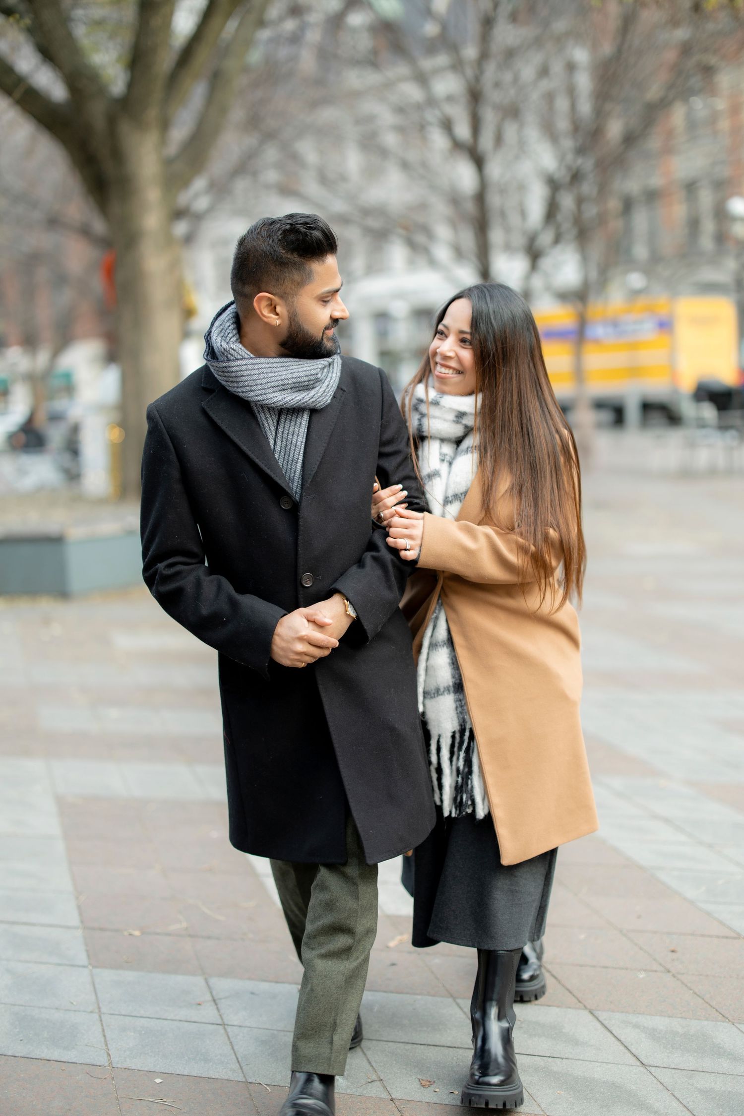 A couple sharing a joyful moment while walking through an urban plaza.