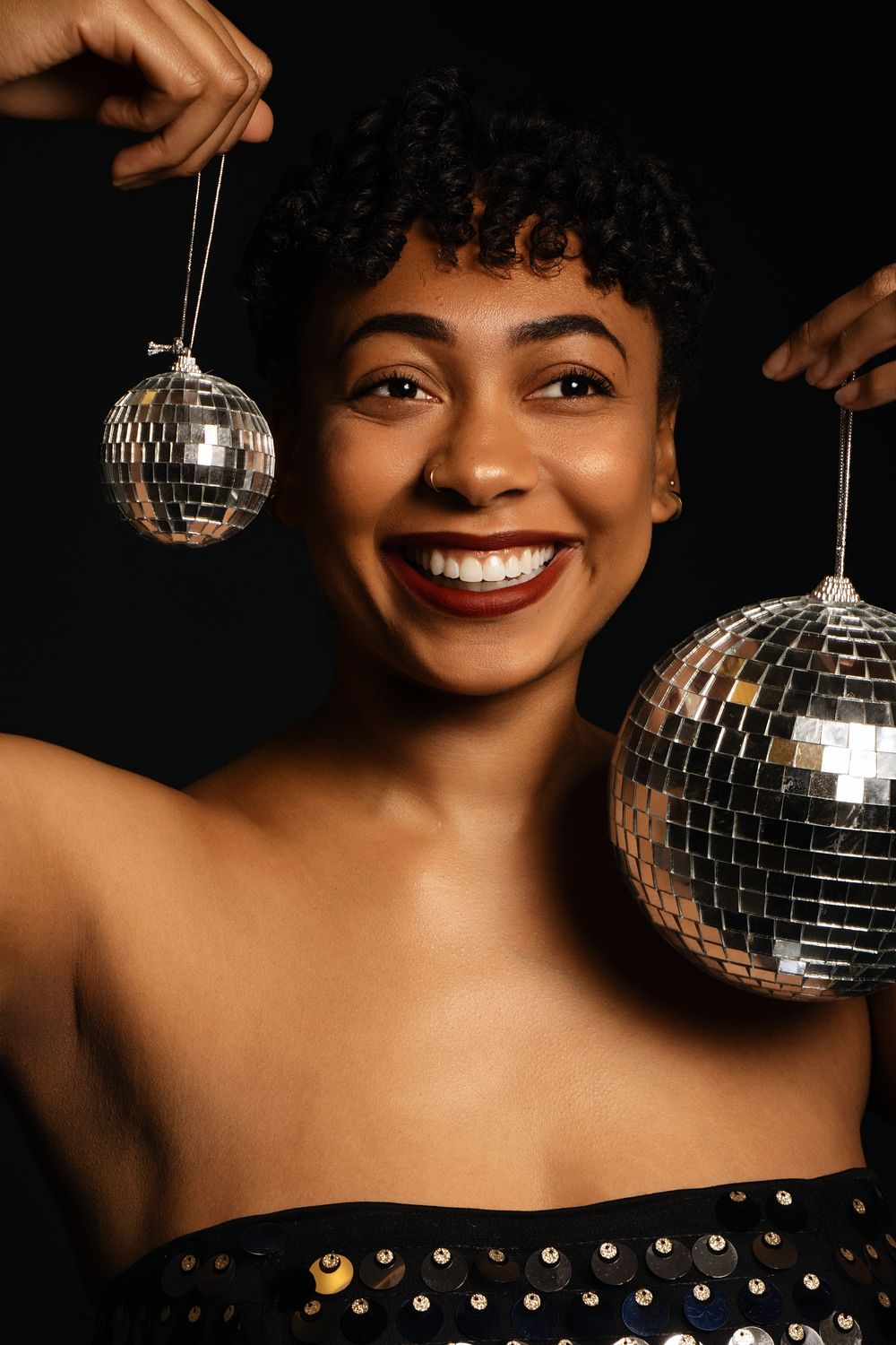 Studio portrait with disco ball and sequined outfit creating glamorous disco vibes.