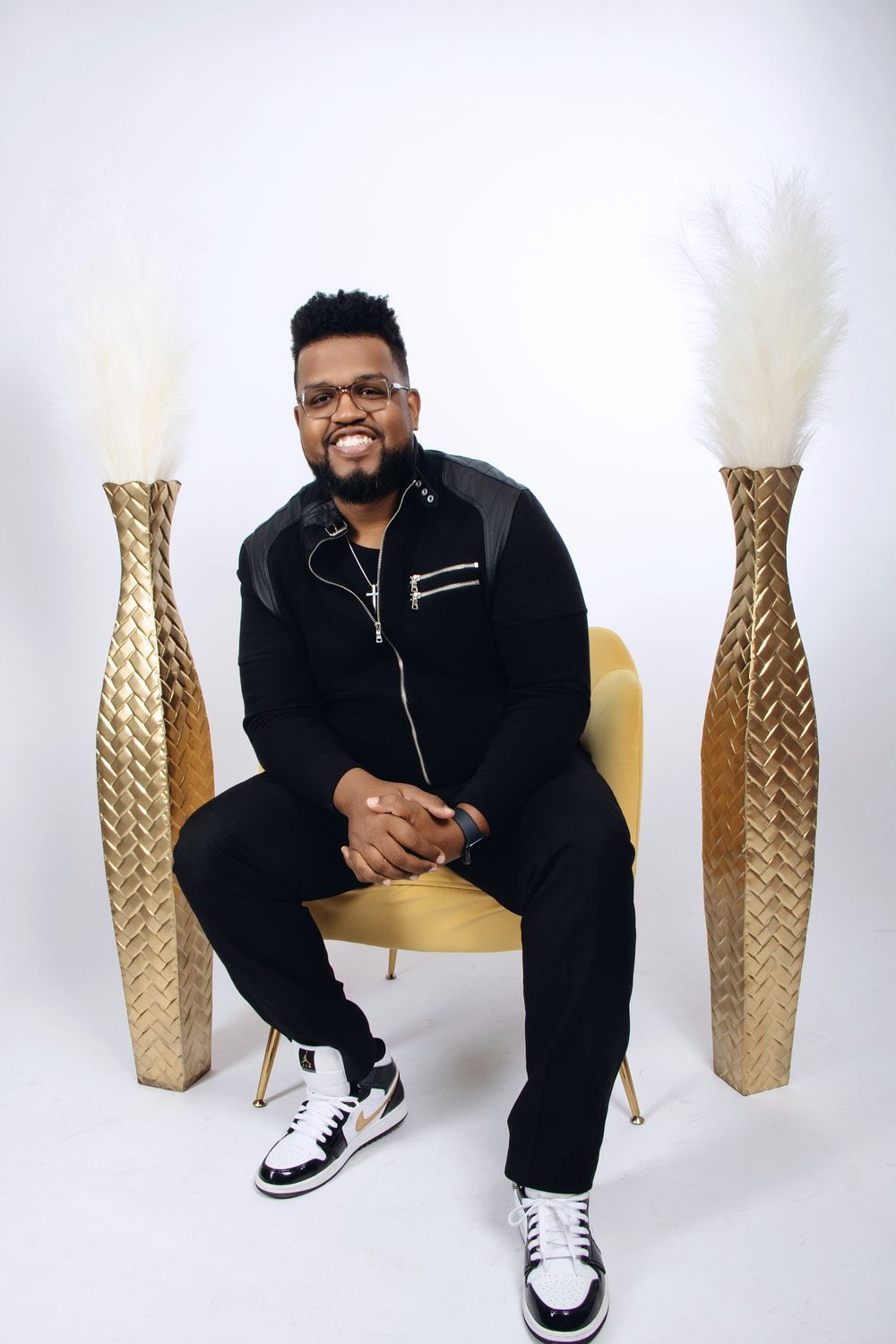 Professional studio photo shoot featuring casual black athleisure wear and white sneakers against a white background.