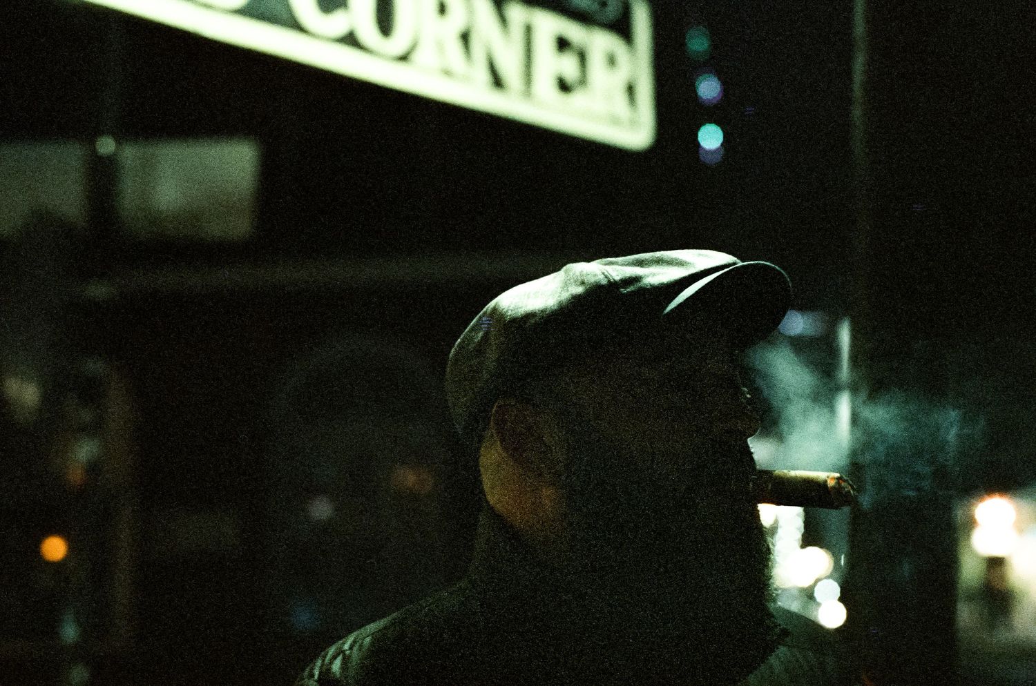 Side profile of someone wearing a dark cap against a nighttime urban backdrop.