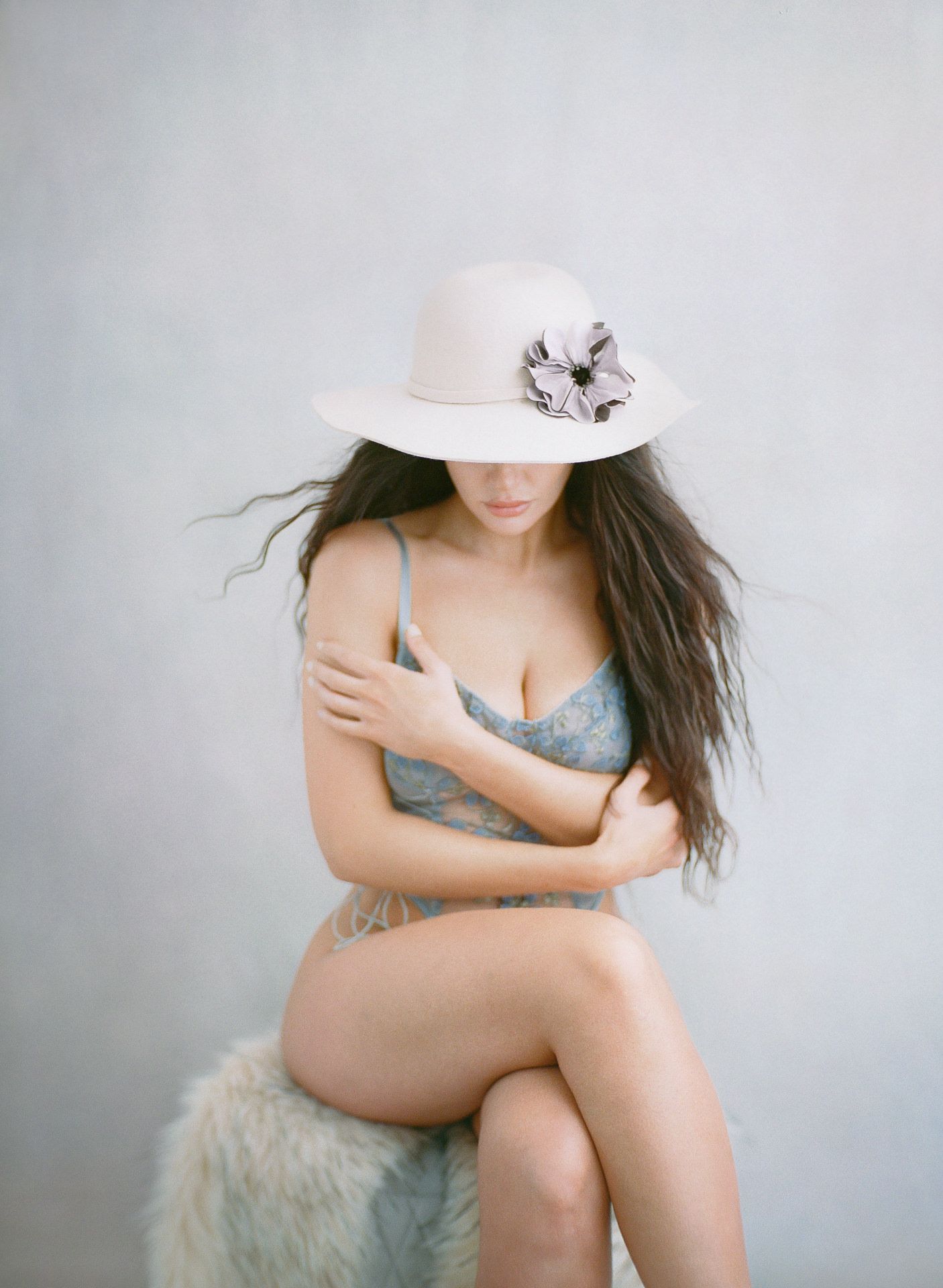 Intimate portrait with white hat and flowing hair against light background.