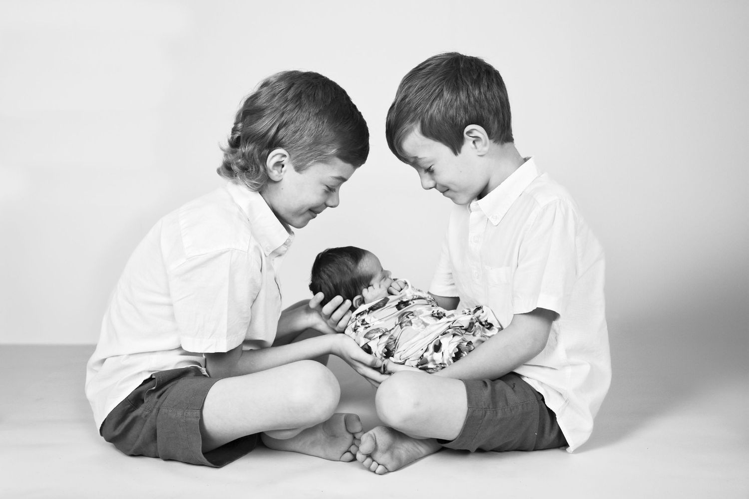 Two siblings hold newborn brother sibling newborn session with siblings in studio in Carlsbad New Mexico. Newborn Photography. Roswell NM