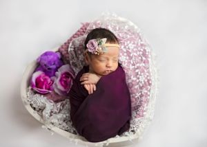 Sleeping baby wrapped in purple swaddle laying in prop. #newbornphotography #babypictures #newbornphotographer #carlsbadNM #RosewellNM