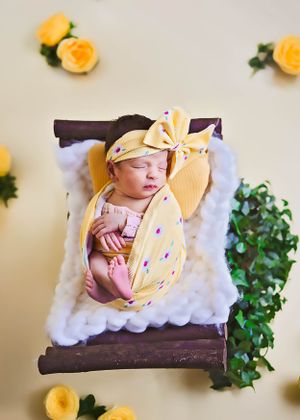 A sleeping newborn wrapped in yellow fabric with a bow headband#carlsbadNM #RosewellNM #artesiaNM #hobbsNM #cutebabypictures