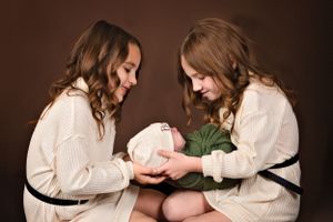 Two siblings hold newborn brother sibling newborn session with siblings in studio in Carlsbad New Mexico. Newborn Photography. Roswell NM