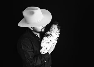 A person wearing a white cowboy hat holding newborn baby. #CarlsbadNM #NewbornPhotographer #NewbornPictures #Roswell #NewMexicoPhotographer