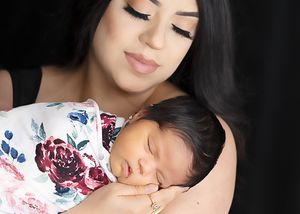 A sleeping newborn in a white floral swaddle rests peacefully. #NewbornwithFamilyPhotography #Artesia #Carlsbad #Roswell #NewMexico #Newborn