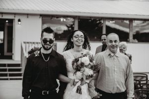 Black and white wedding photo showing three people standing together outdoors.