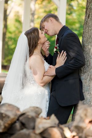 A romantic wedding couple shares intimate kisses in a sequence of photos outdoors with trees in the background.