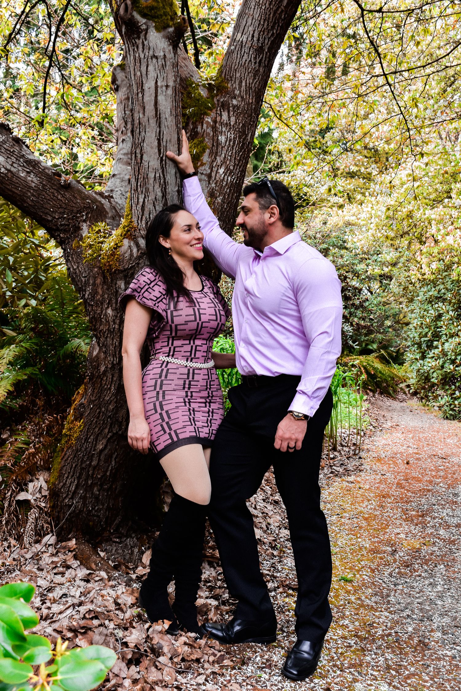 Romantic couple posing on a forest trail with ferns and evergreens in the background. Perfect for engagement or couple sessions