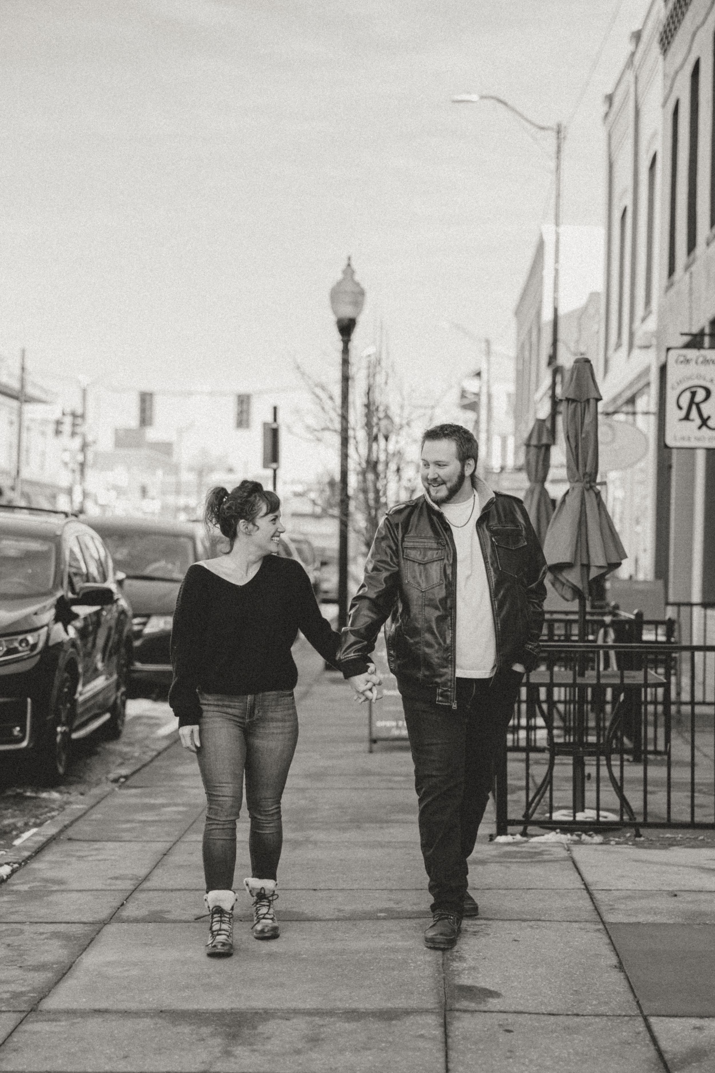 A couple walks together along an urban sidewalk in black and white photography.