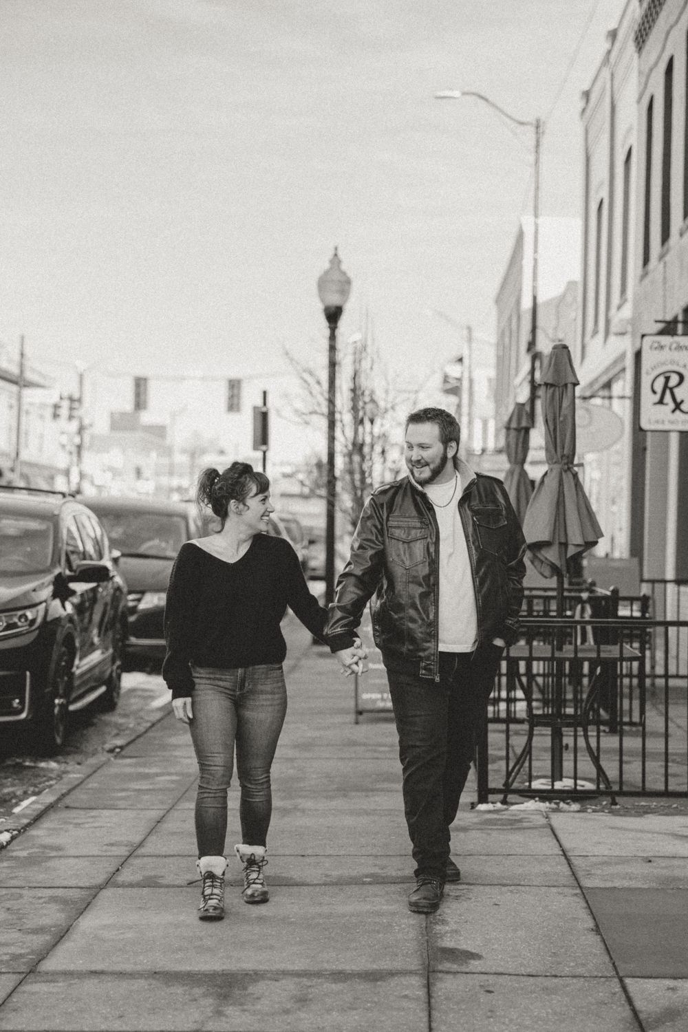 A couple walks together along an urban sidewalk in black and white photography.