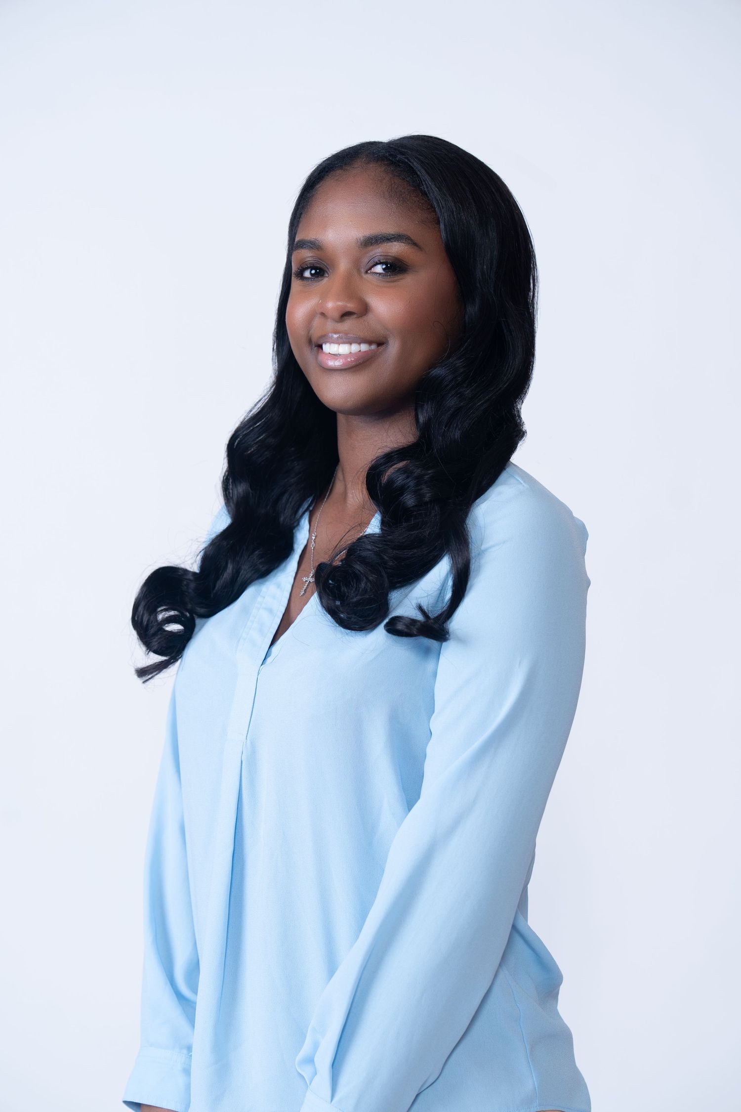 Professional portrait of someone wearing a light blue blazer against white background.