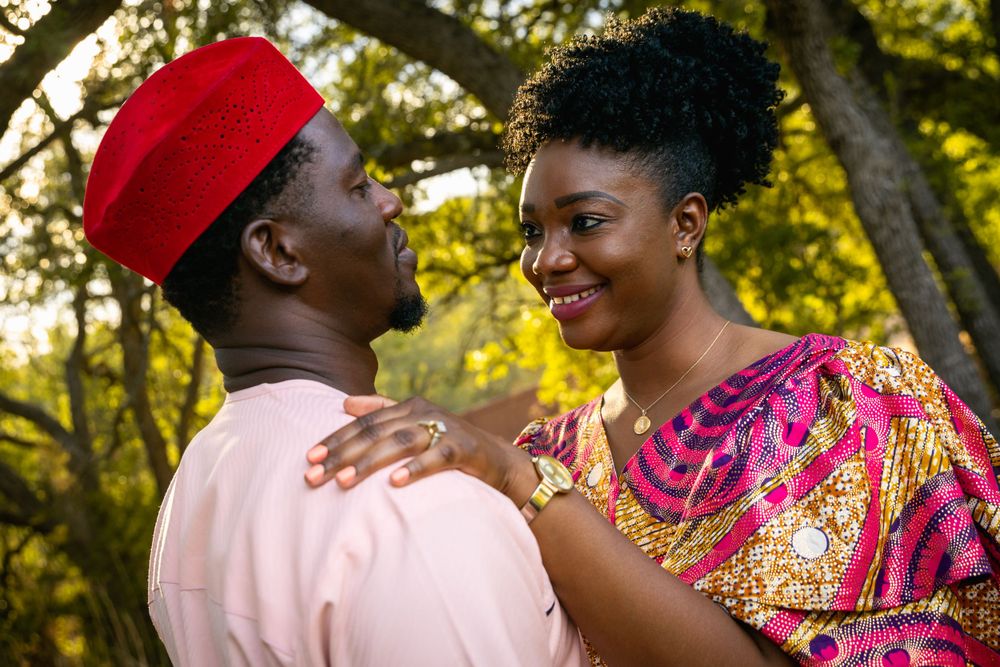 Couple sharing romantic moment outdoors wearing traditional African-inspired attire.