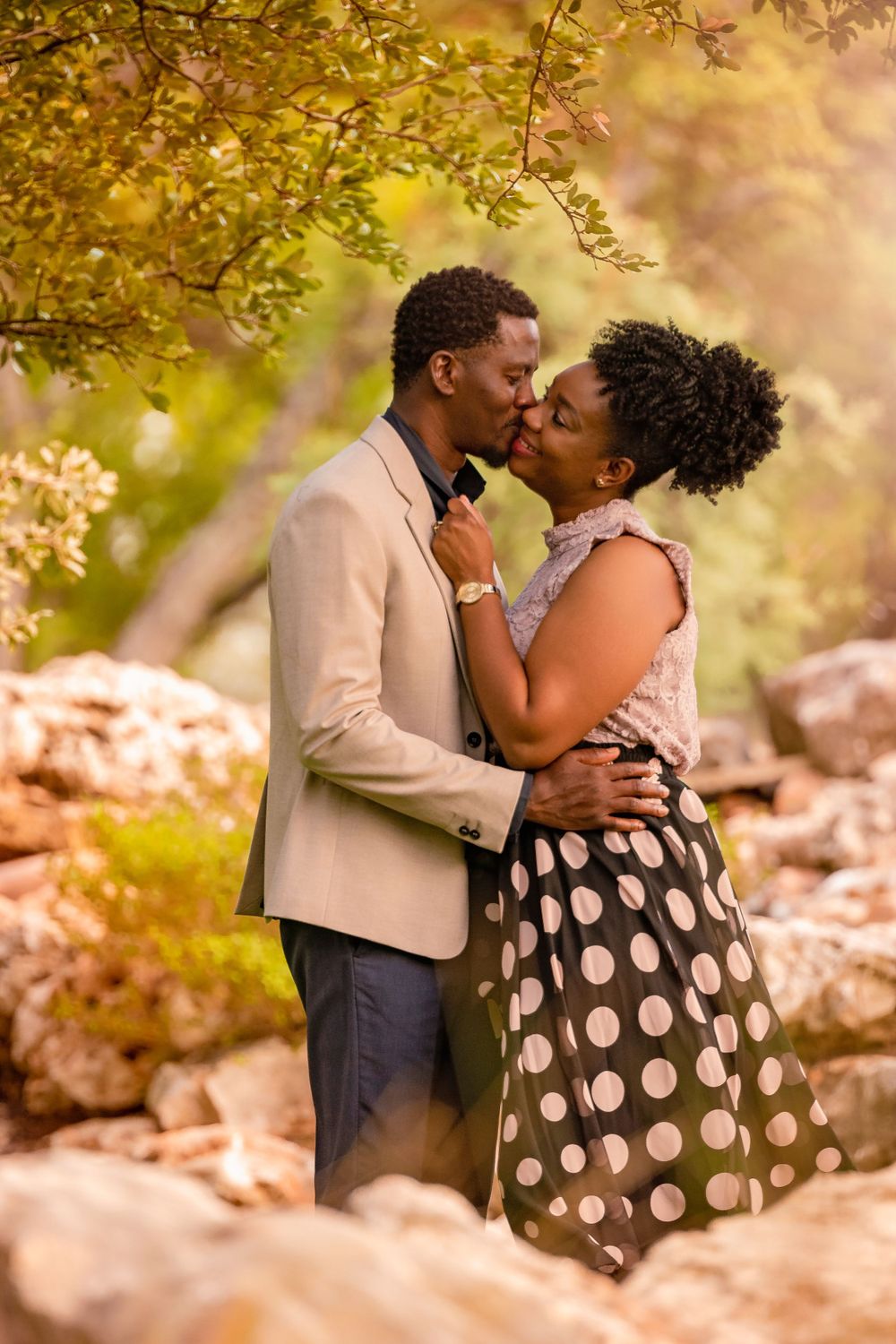 A romantic couple embraces among autumn trees with warm golden lighting.