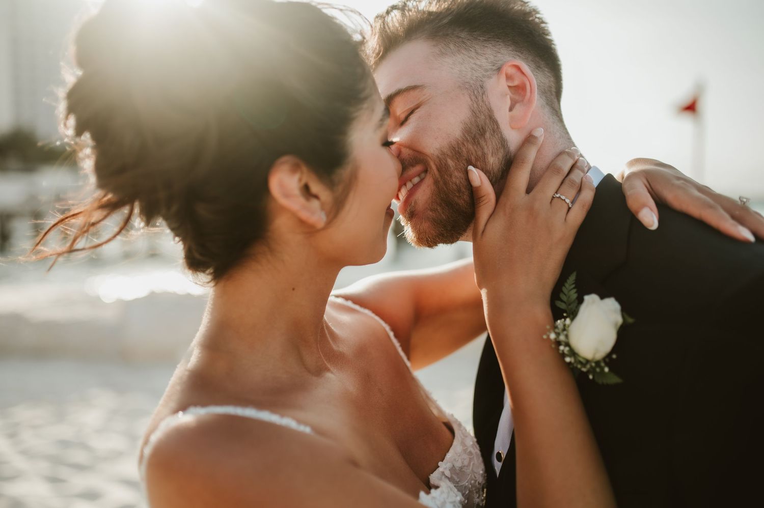 A romantic wedding couple shares an intimate kiss during a golden sunset on the beach.