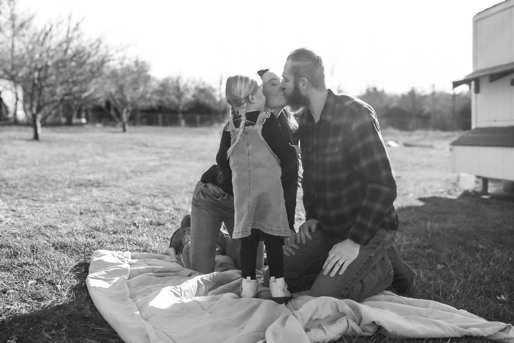 A couple sits together outdoors during golden hour in a casual photoshoot setting.