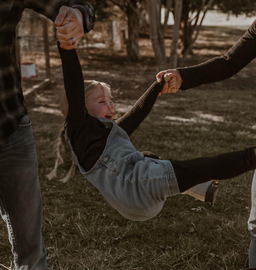 Two people share a playful moment while sitting on grass during sunset.