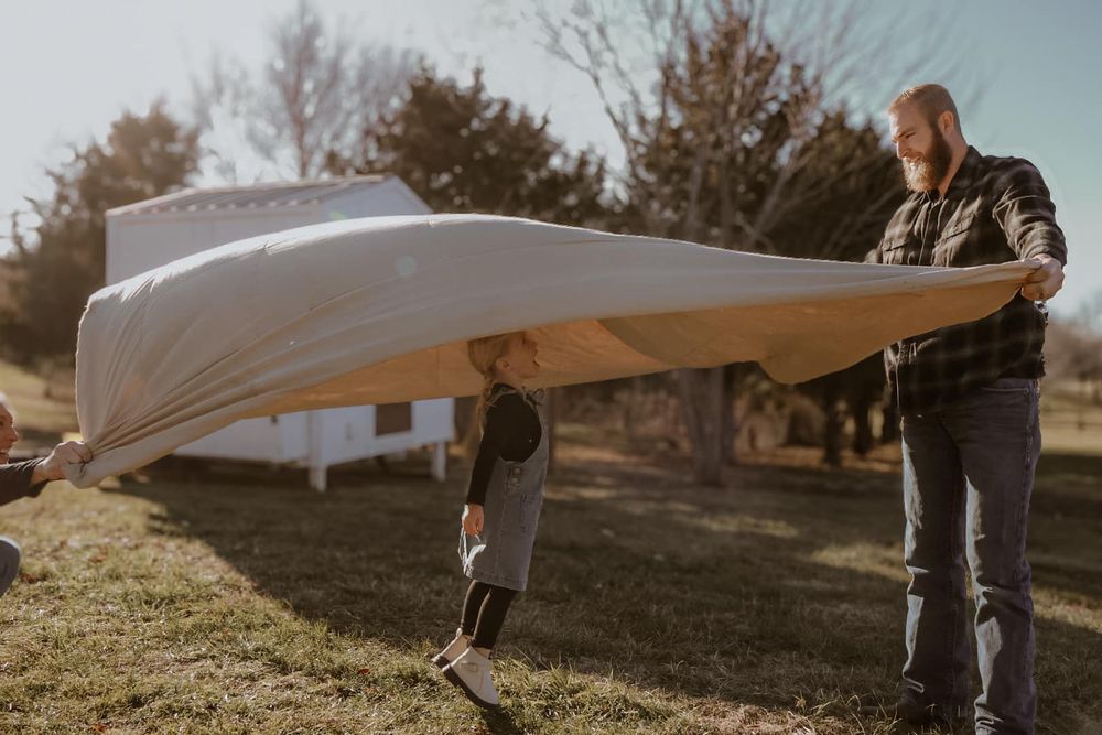 People holding a white fabric flowing in the wind during an outdoor photoshoot.