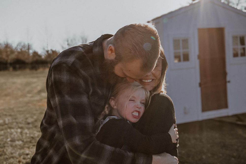 Candid moment captured between two people during sunset near a white building.