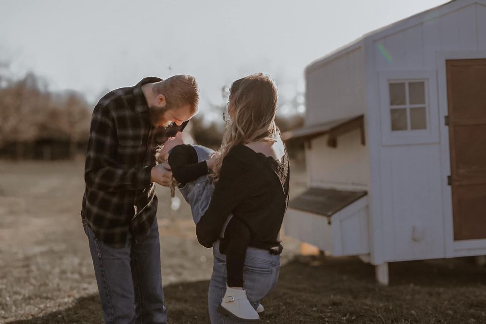 Outdoor family photoshoot scene with a white building in the background during golden hour.