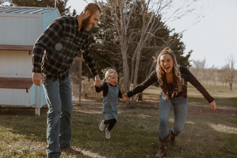 A playful moment captured as a child jumps while holding hands with others on a lawn.