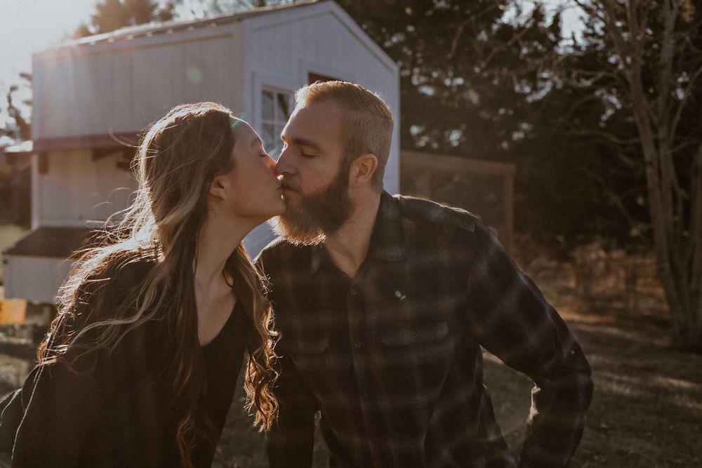 A romantic sunset moment shared between two people in front of a rural building.